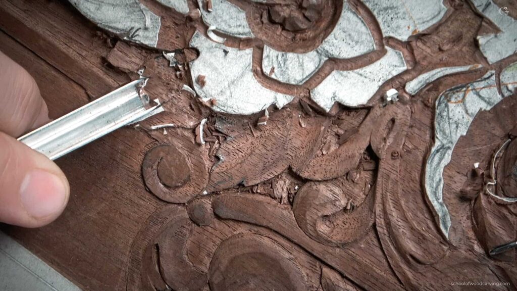 A person is using a carving tool to carve a piece of wood. Furniture Panel
