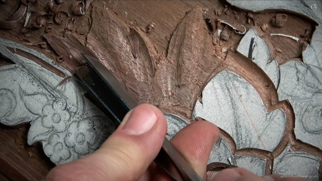 A person is carving a piece of wood with a Carving Gouge to create furniture panel.