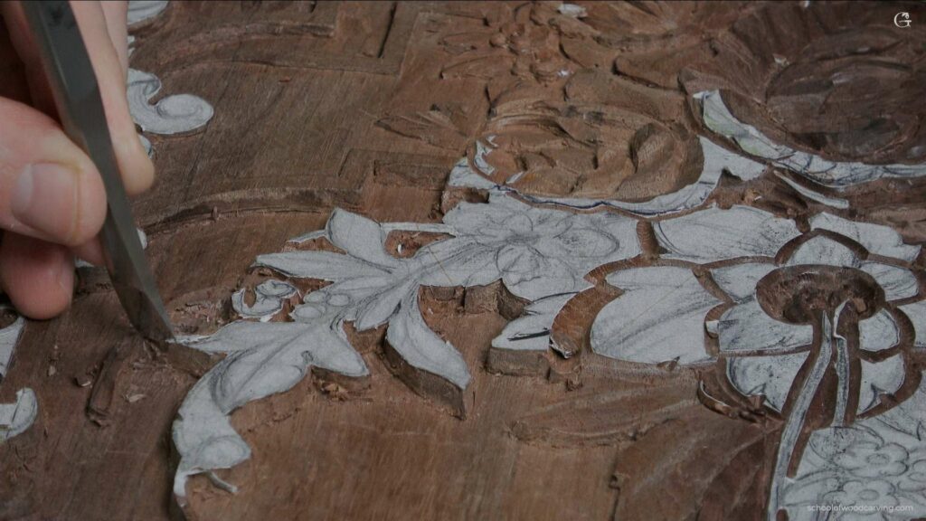 A person is carving a piece of wood with a gouge.