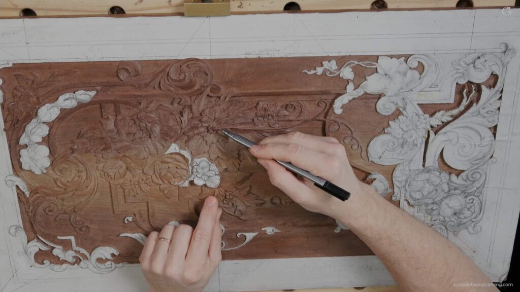 A person using a pencil to draw on a piece of wood.