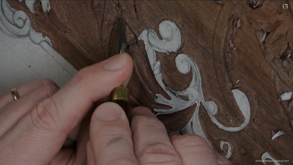 A person is carving a design on a piece of wood using a knife.