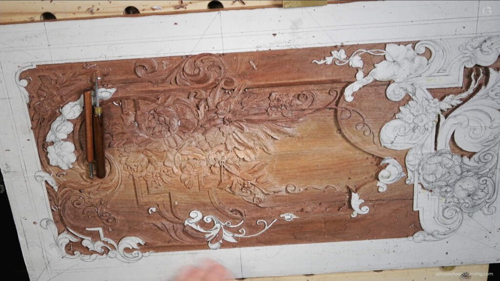 A person is carving a furniture panel on a table.