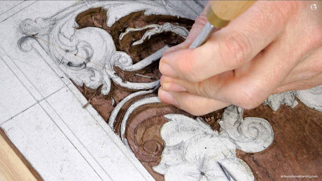 A close-up of a person's hands carving intricate floral patterns into a wooden panel during woodcarving lessons using a chisel.