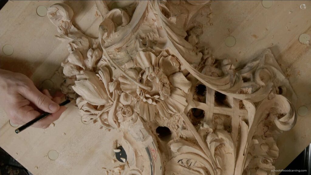 WOODCARVING LESSONS: A hand is holding a chisel and carving beautiful flower patterns into a big, light-colored piece of wood. You can see shapes like leaves, flowers, and other fancy designs on the workshop table. The woodcarving work by Woodcarver Grabovetskiy shows fine details and looks three-dimensional. This image is perfect for anyone looking for woodcarving lessons or tutorials because it highlights expert skills in making detailed patterns in wood. If you want to learn how to carve wood with such skill, courses by Woodcarver Grabovetskiy are a great place to start. - Wood Carving tutorials