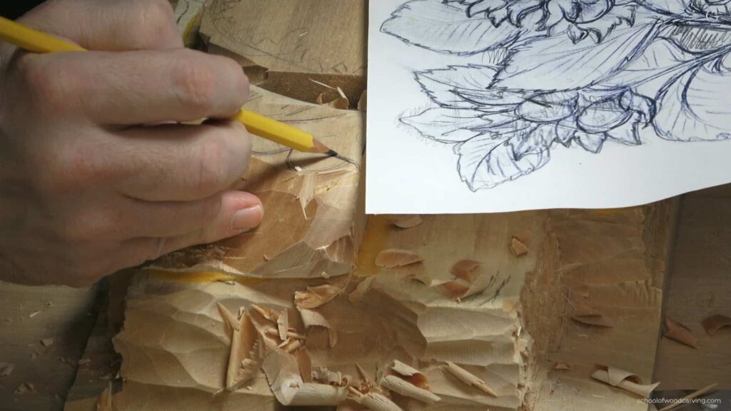 WOODCARVING LESSONS: Woodcarver Grabovetskiy uses a yellow pencil to carve flowers in wood, with shavings and a flower sketch as a guide nearby. - Wood Carving tutorials