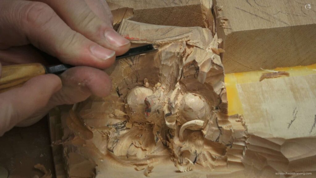 WOODCARVING LESSONS: Woodcarver Grabovetskiy uses a small chisel to carve a hazelnut pattern in wood. Wood shavings are around the unfinished design. - Wood Carving tutorials
