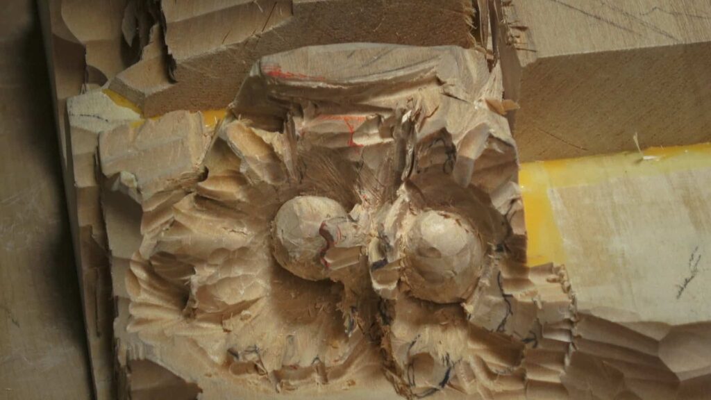 WOODCARVING LESSONS: Close-up of Woodcarver Grabovetskiy carving a wood block with rough hazelnuts shapes, chisel marks, guide lines, and yellow tape. - Wood Carving tutorials